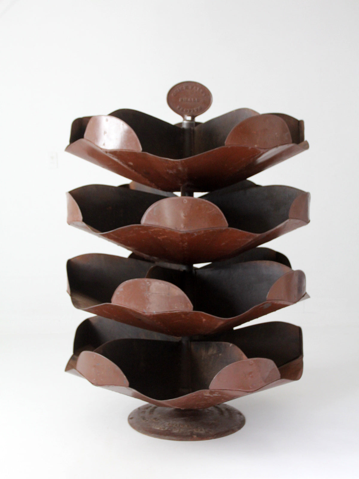antique industrial brown metal rotating hardware stand with tiered design on a white background