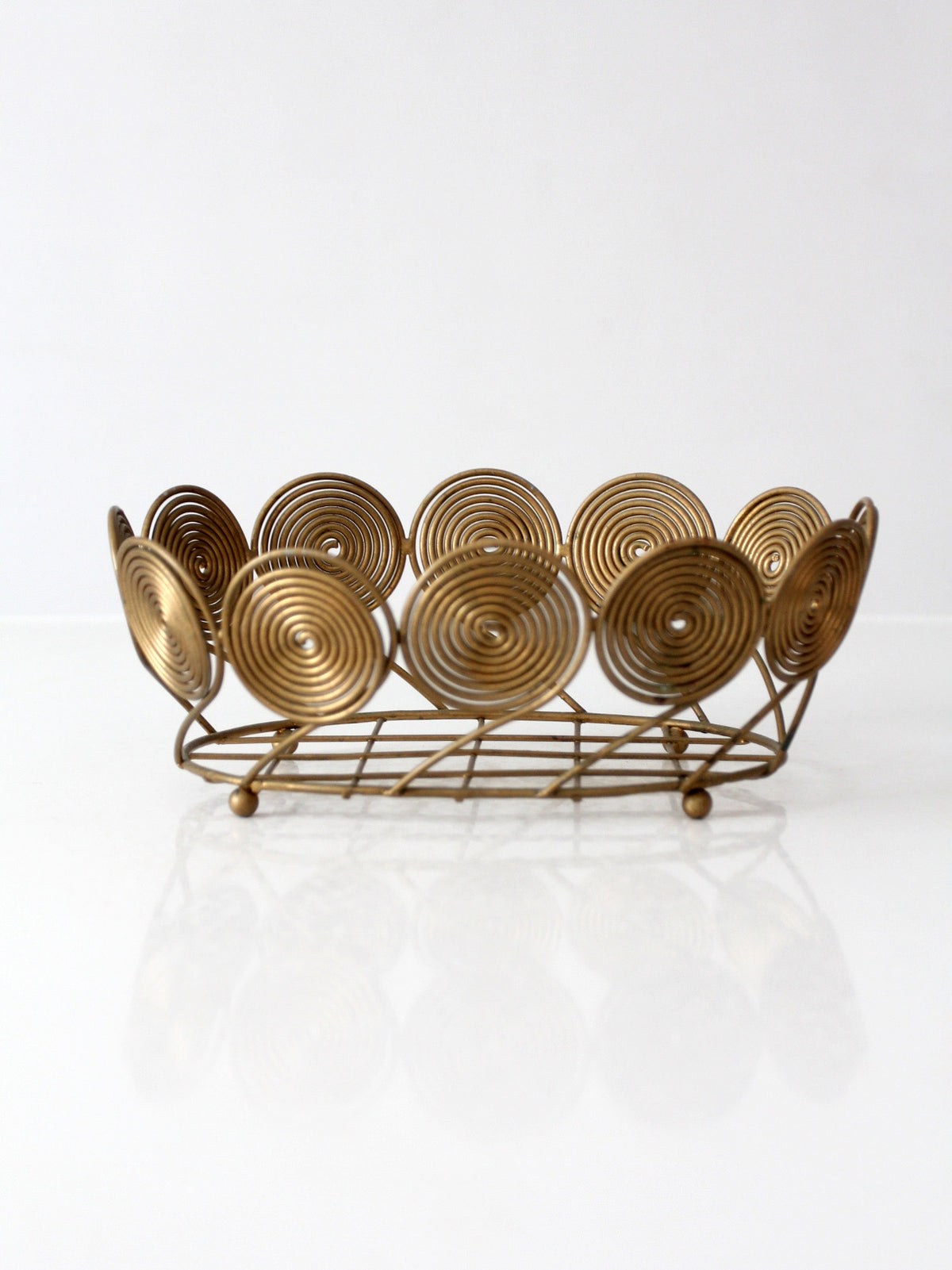 mid-century Decorative gold bowl with spiral designs on a white background