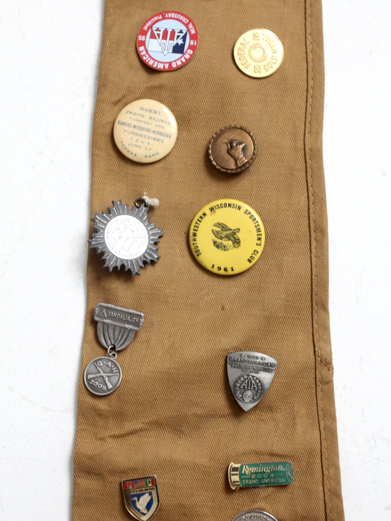 vintage gun club pin collection on Blue Bill canvas rifle case