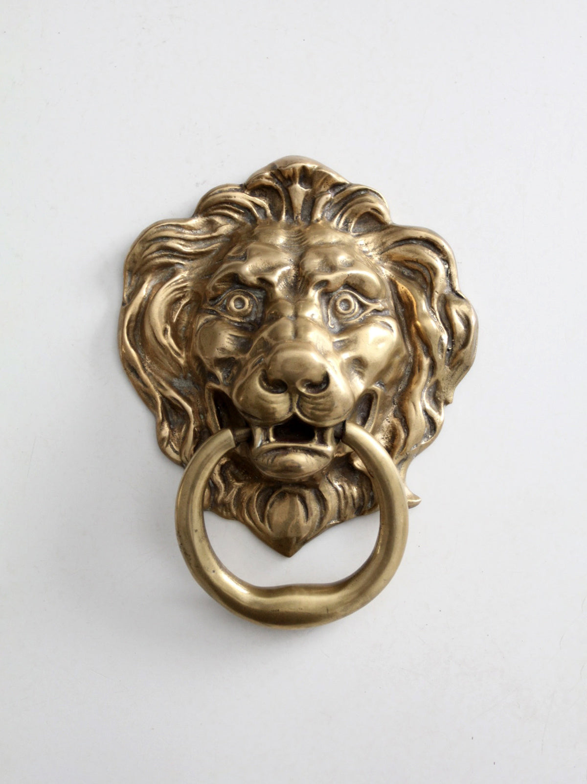 An antique brass lion head door knocker with a ring pull, shown against a plain white background.