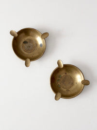 pair of vintage brass ashtrays with embossed medallions