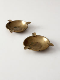 pair of vintage brass ashtrays with embossed medallions