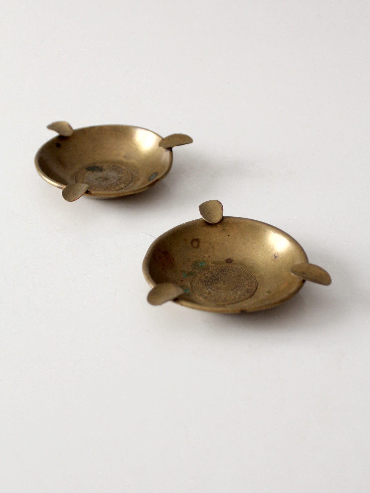 pair of vintage brass ashtrays with embossed medallions
