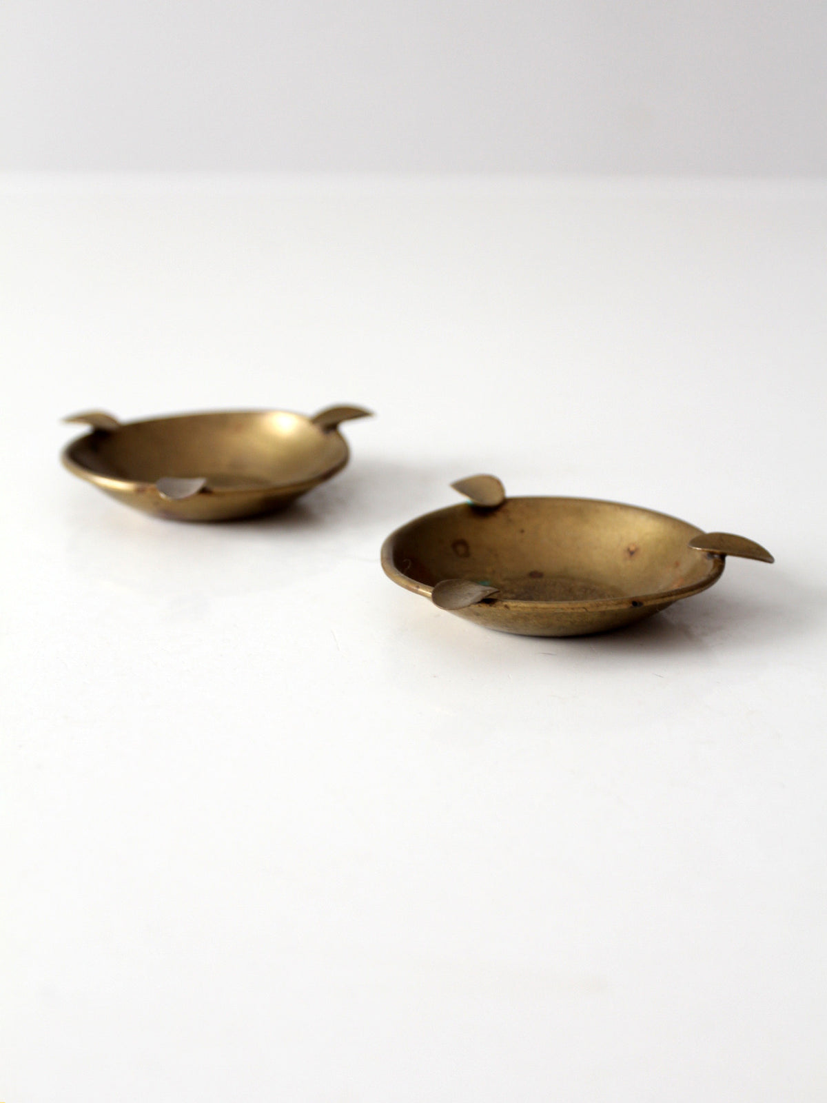 pair of vintage brass ashtrays with embossed medallions