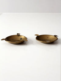 pair of vintage brass ashtrays with embossed medallions