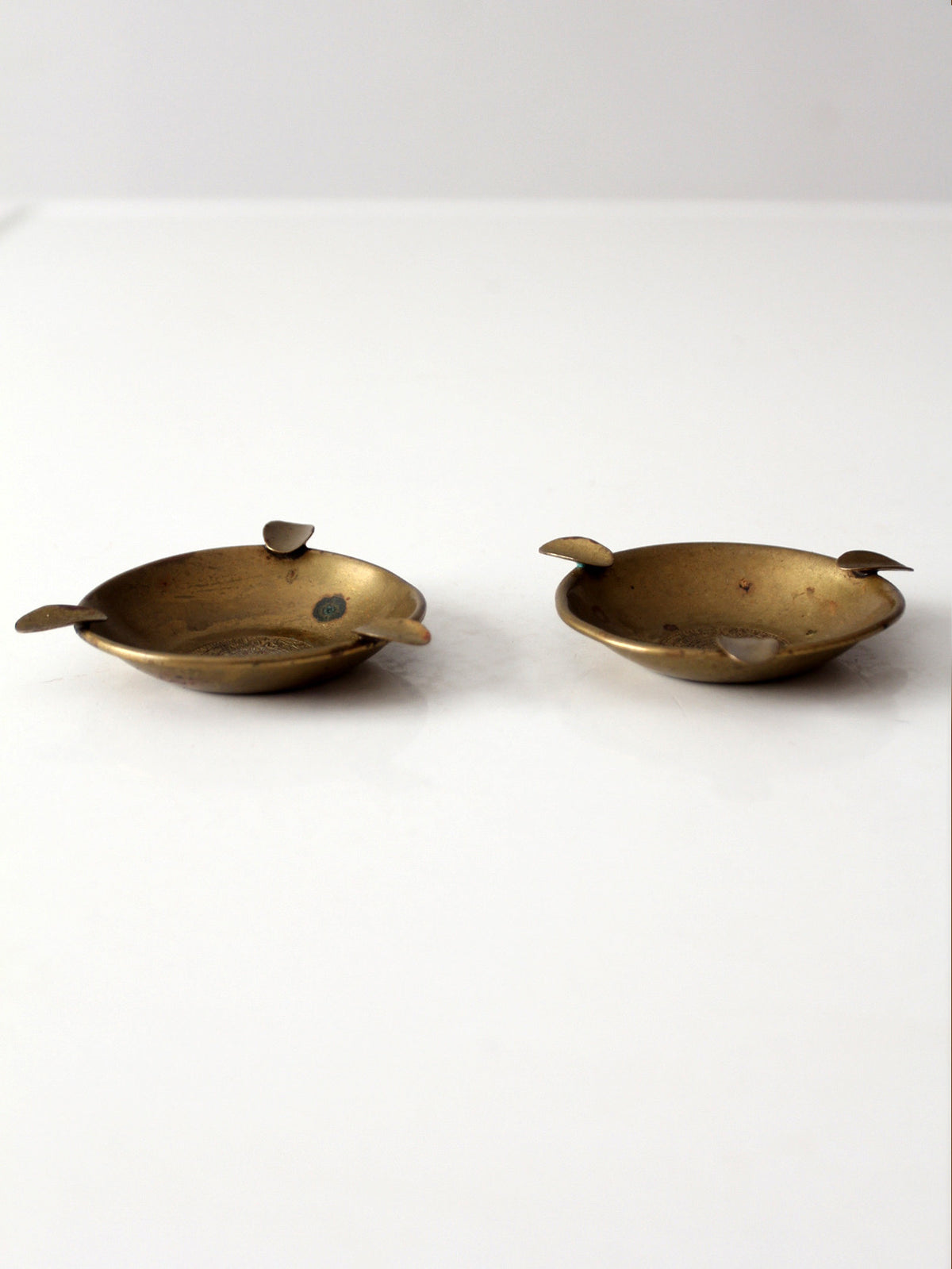 pair of vintage brass ashtrays with embossed medallions