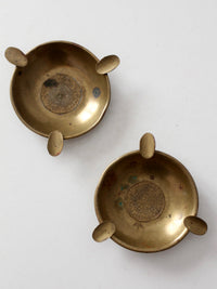 pair of vintage brass ashtrays with embossed medallions