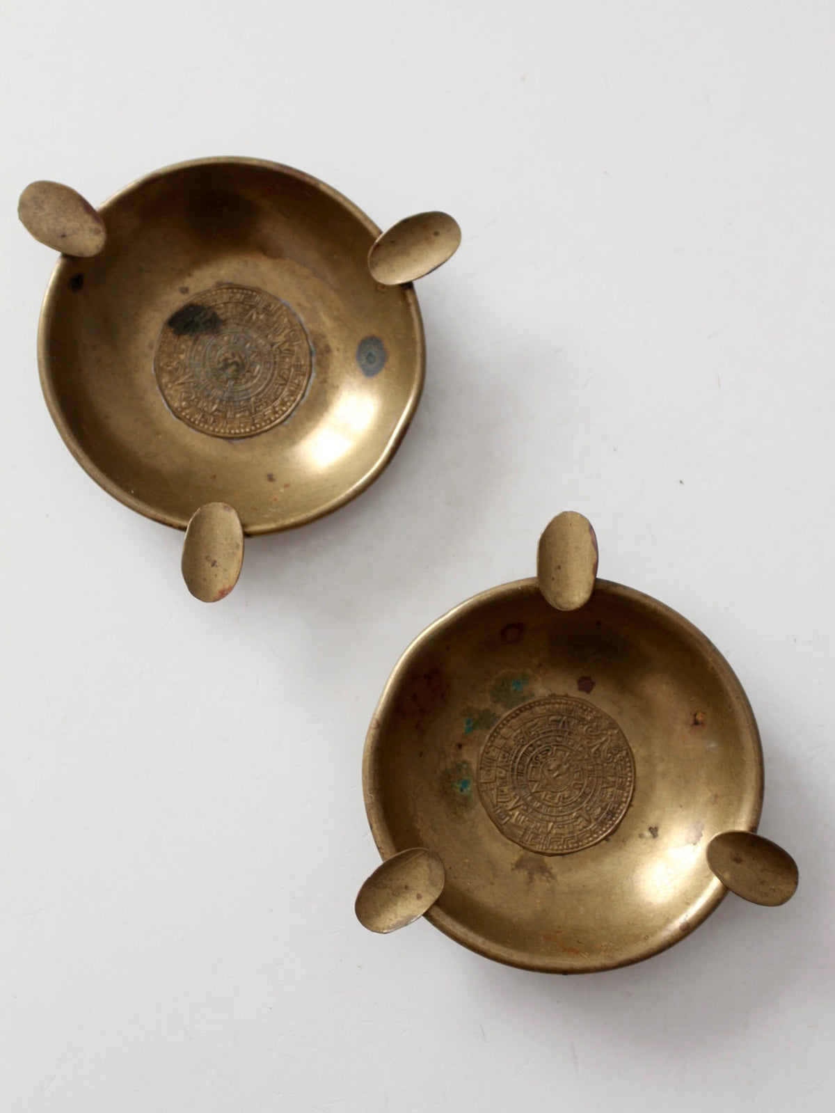 pair of vintage brass ashtrays with embossed medallions