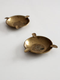 pair of vintage brass ashtrays with embossed medallions