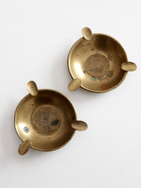 pair of vintage brass ashtrays with embossed medallions