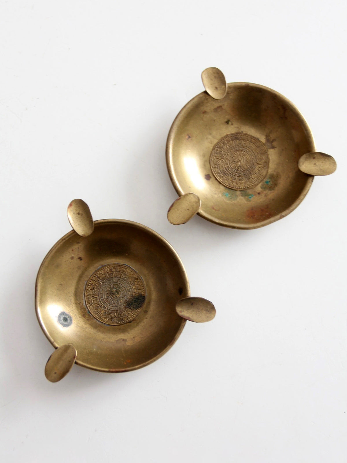 pair of vintage brass ashtrays with embossed medallions