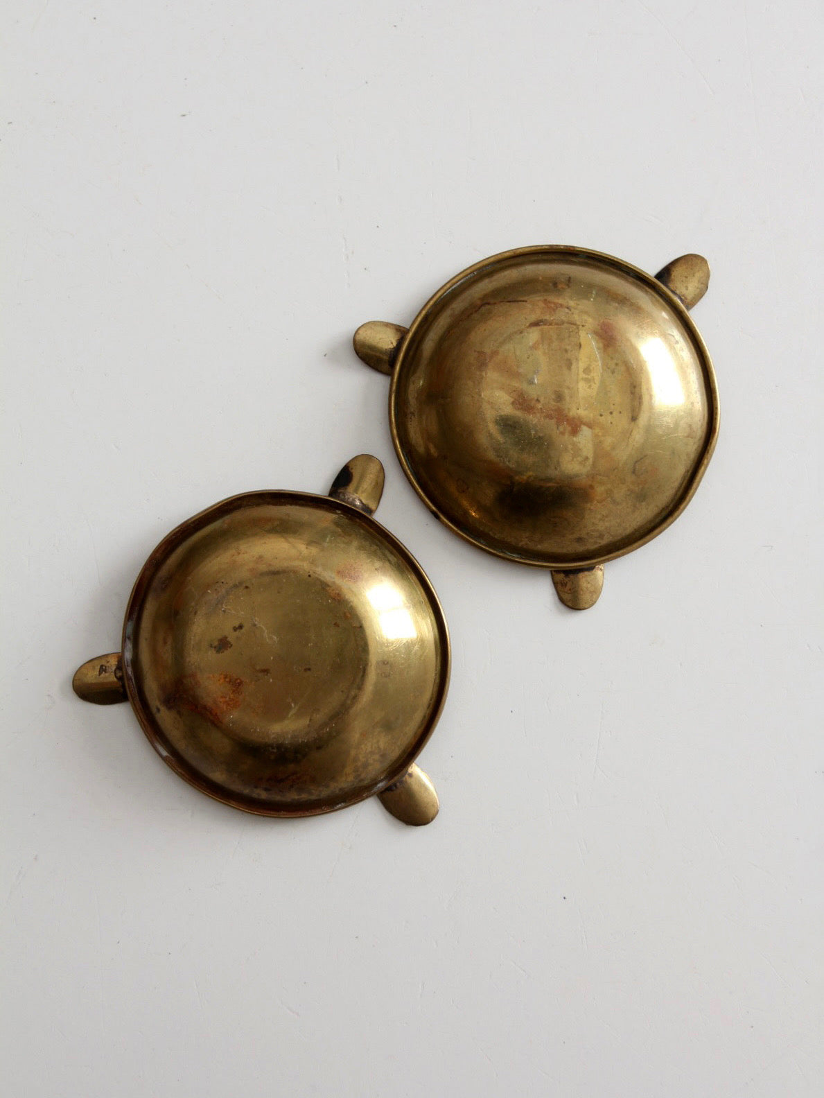 pair of vintage brass ashtrays with embossed medallions