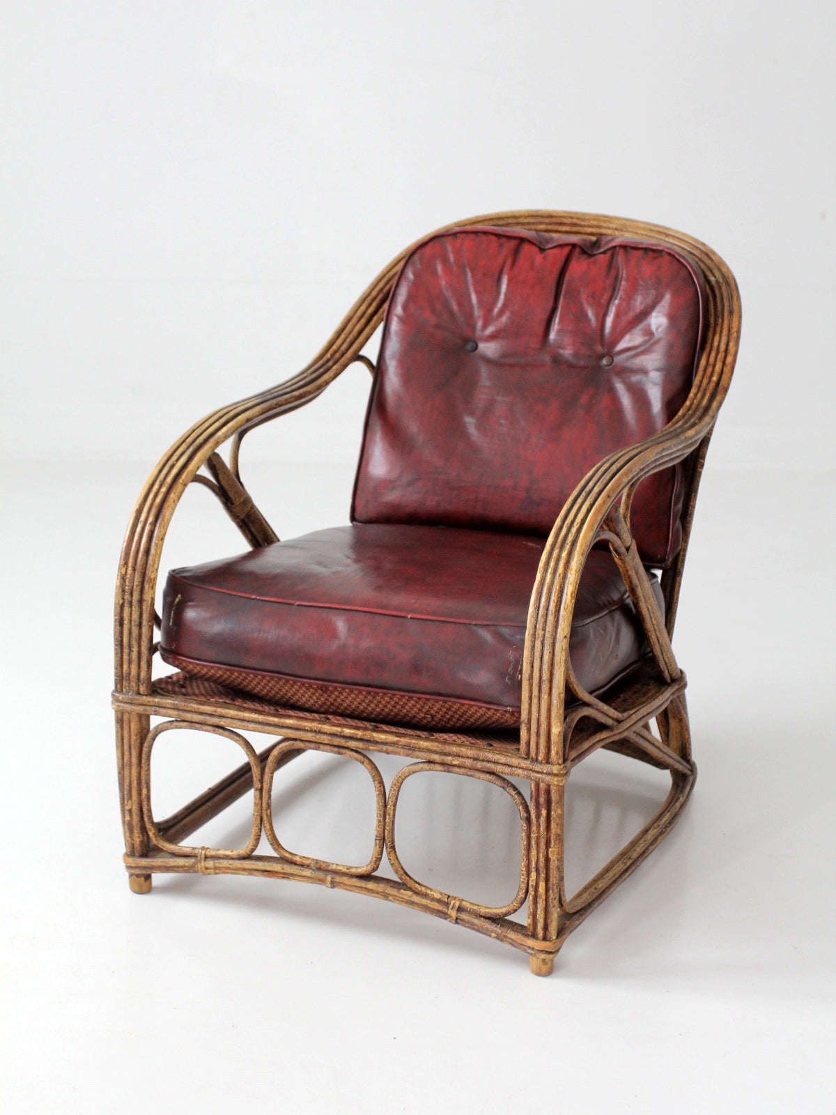 antique rattan lounge chair with oxblood cushions