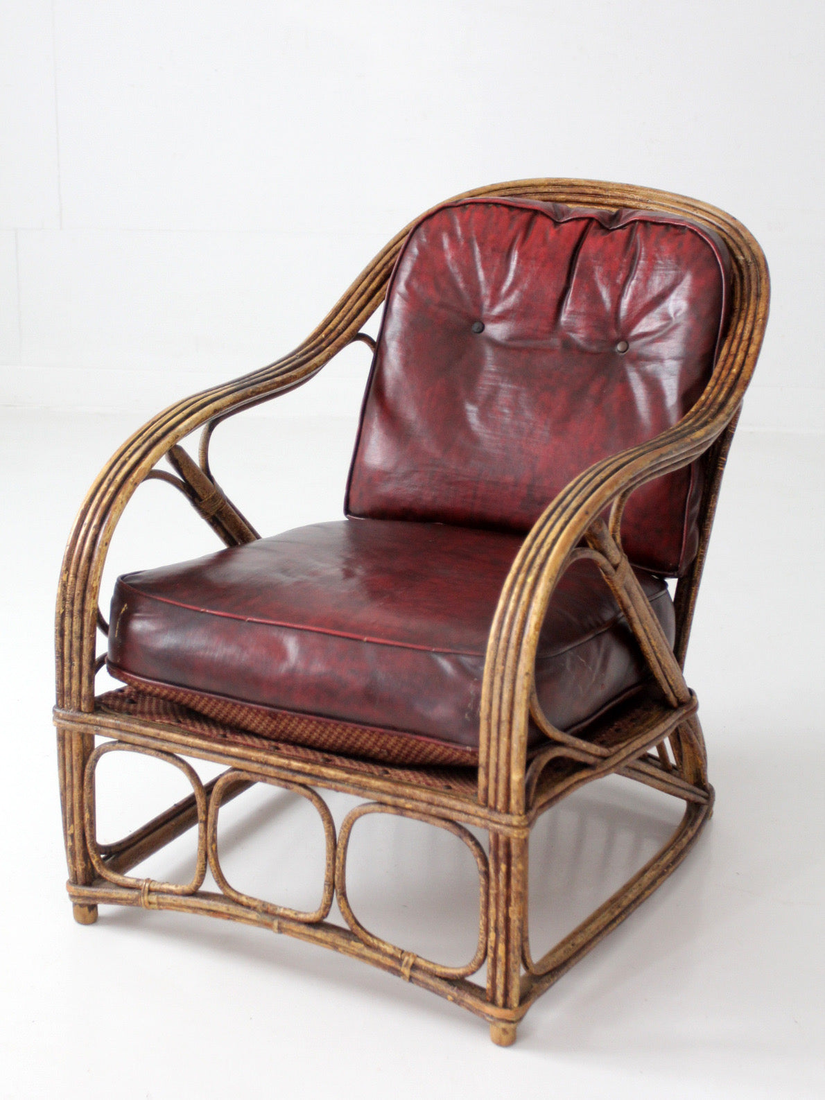 antique rattan lounge chair with oxblood cushions
