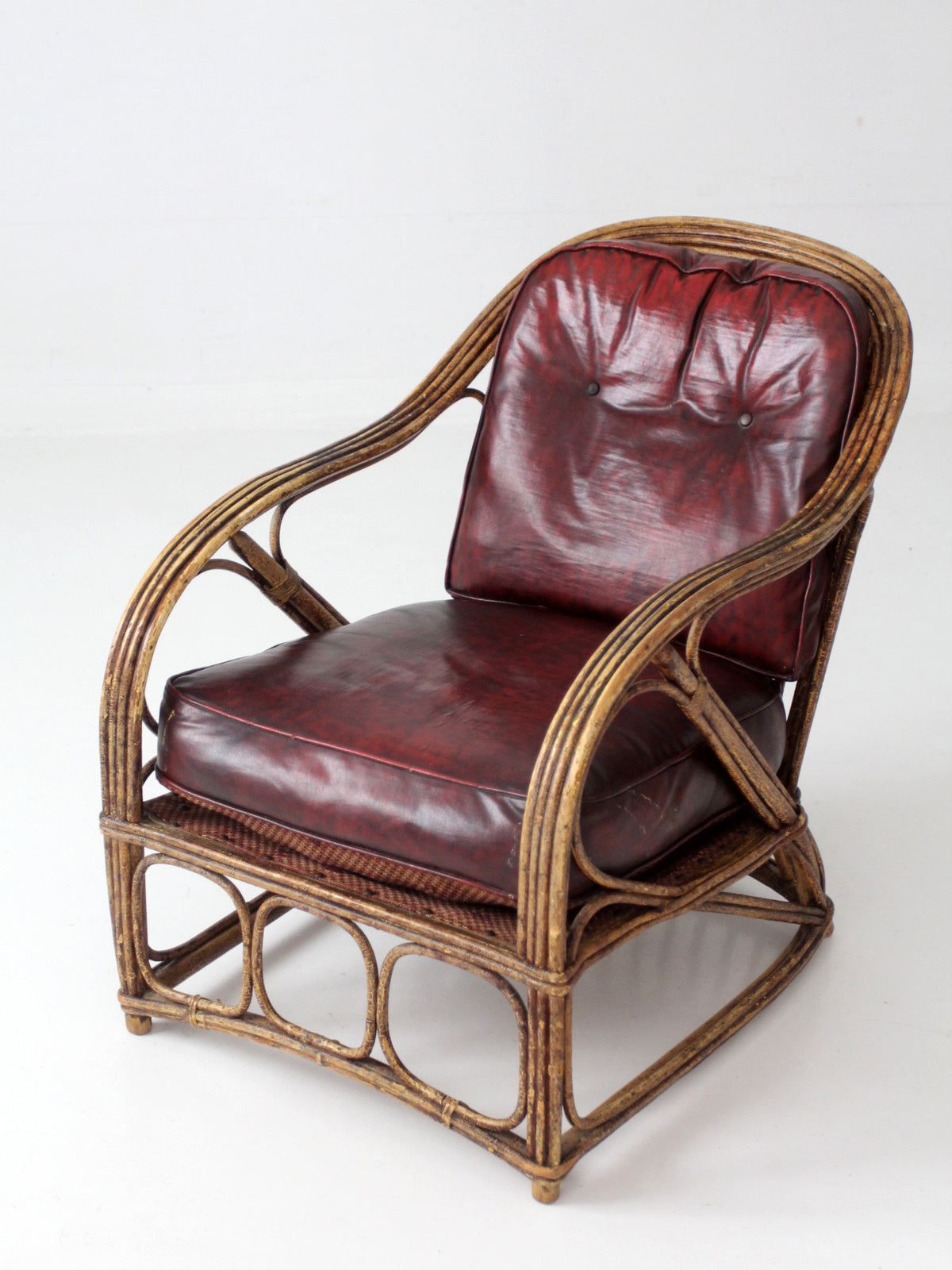 antique rattan lounge chair with oxblood cushions