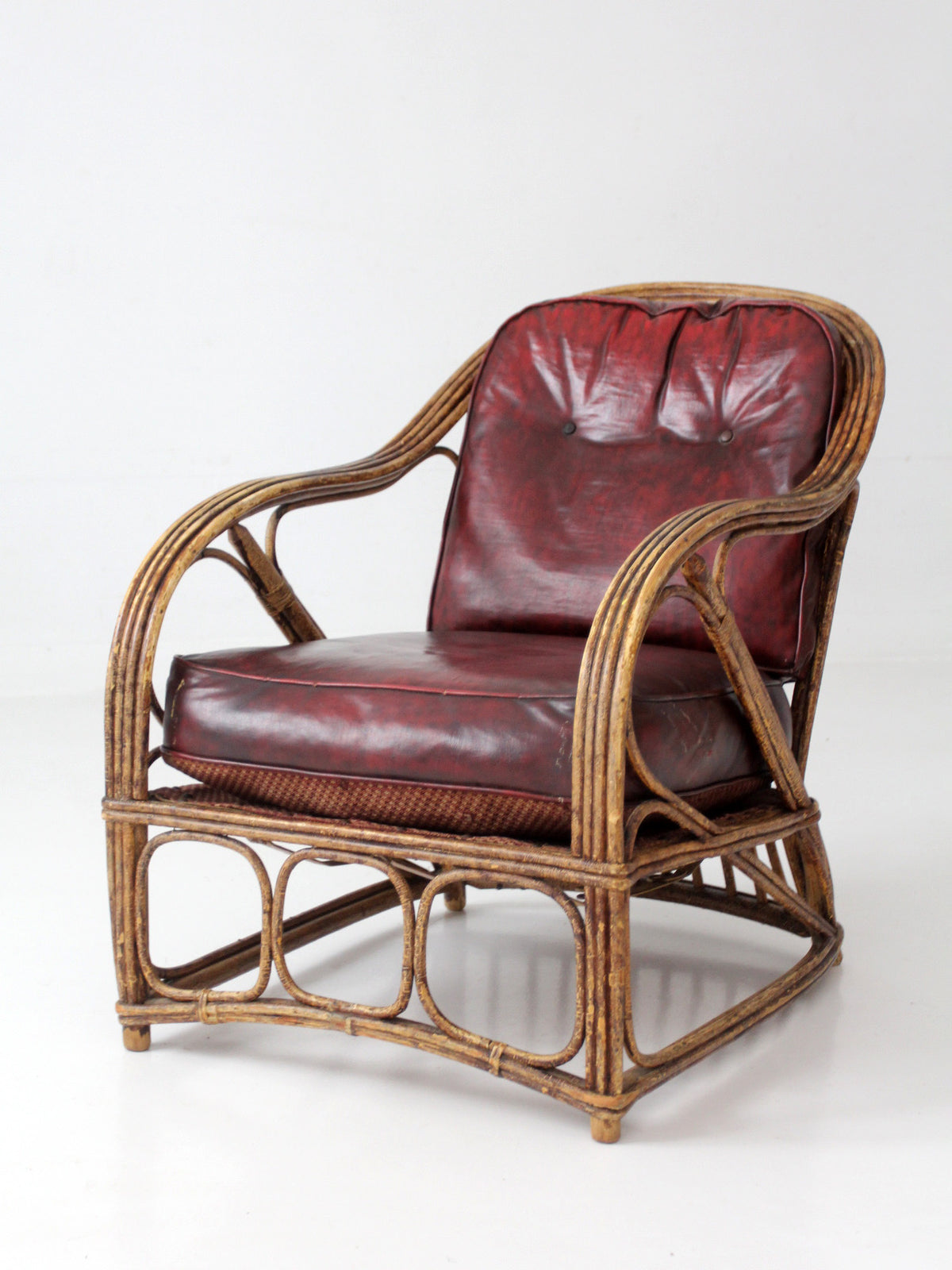 antique rattan lounge chair with oxblood cushions
