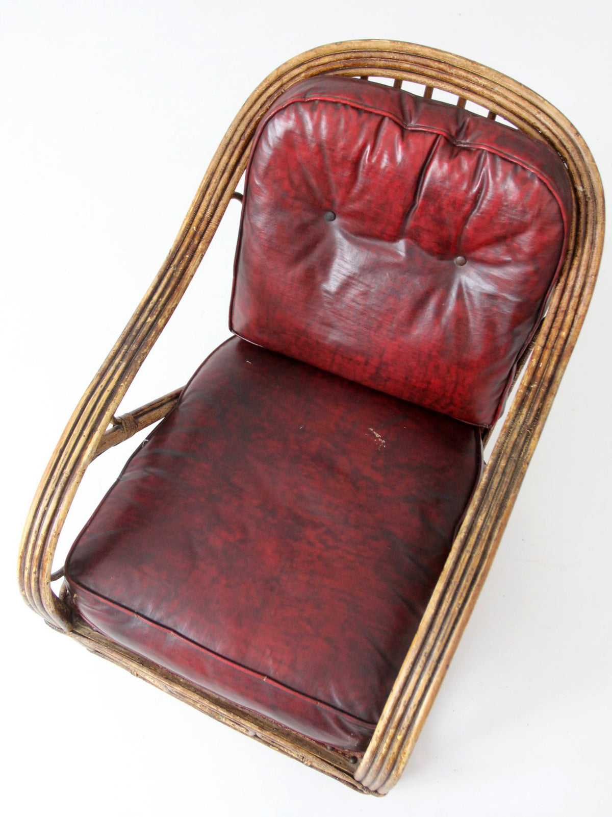 antique rattan lounge chair with oxblood cushions