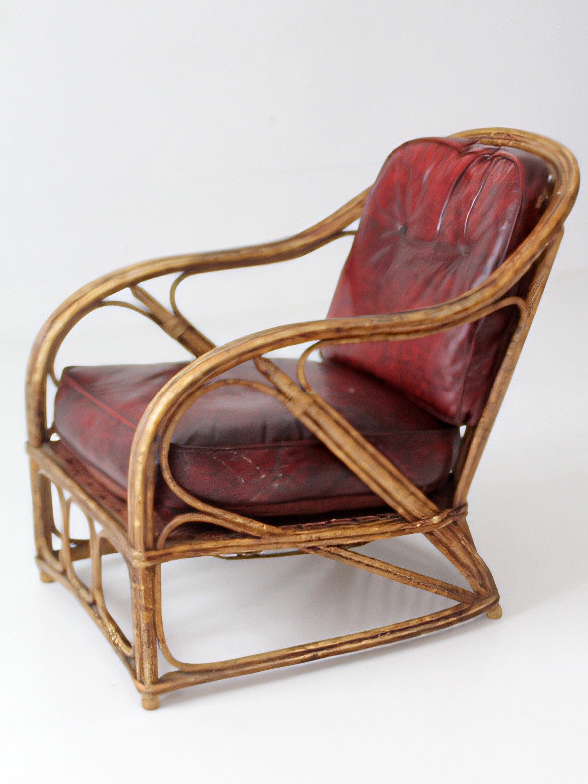 antique rattan lounge chair with oxblood cushions