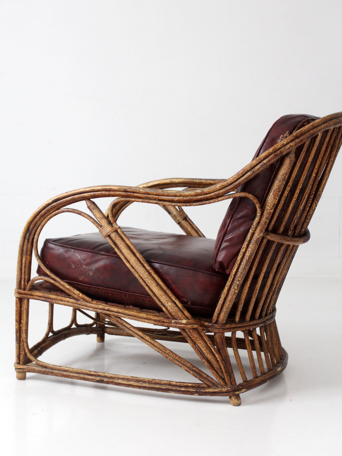 antique rattan lounge chair with oxblood cushions