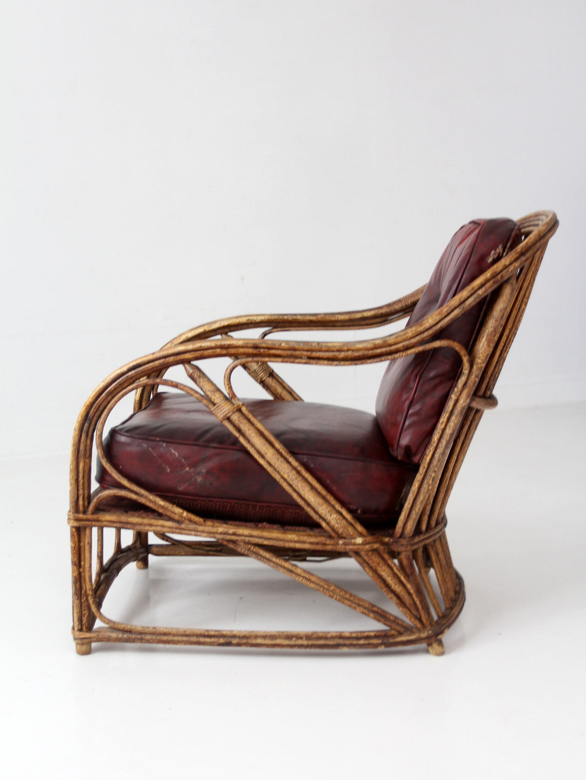antique rattan lounge chair with oxblood cushions