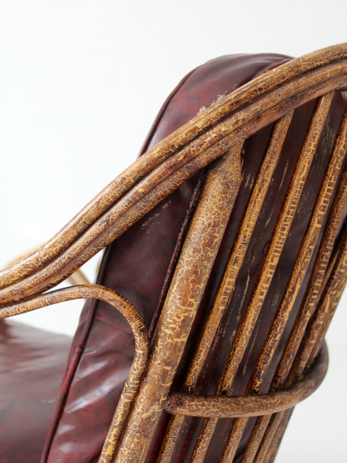 antique rattan lounge chair with oxblood cushions