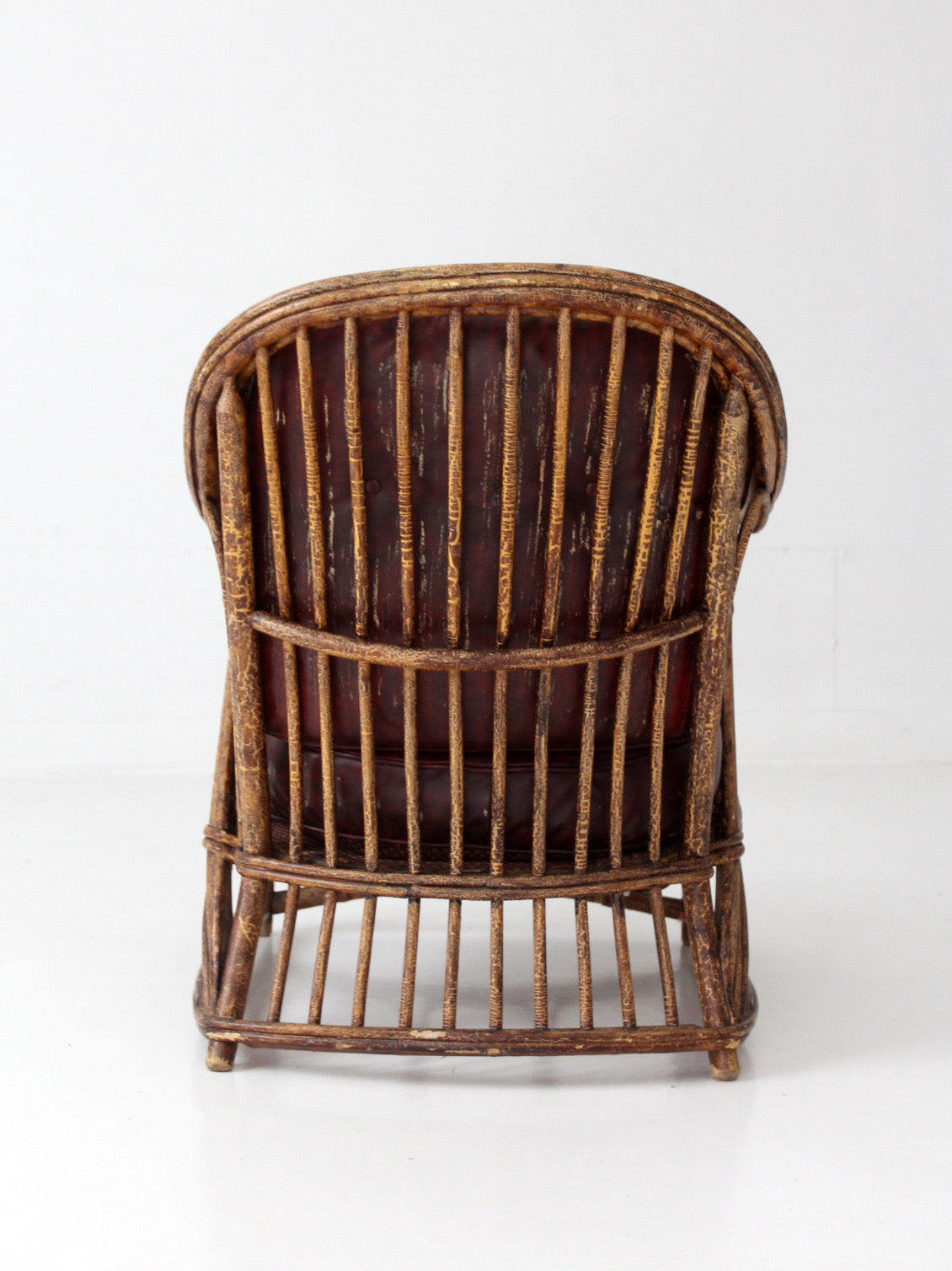 antique rattan lounge chair with oxblood cushions
