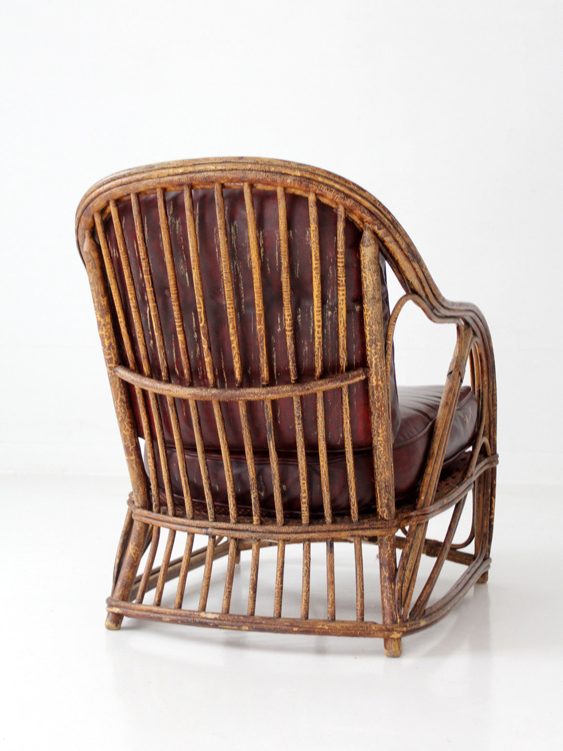 antique rattan lounge chair with oxblood cushions