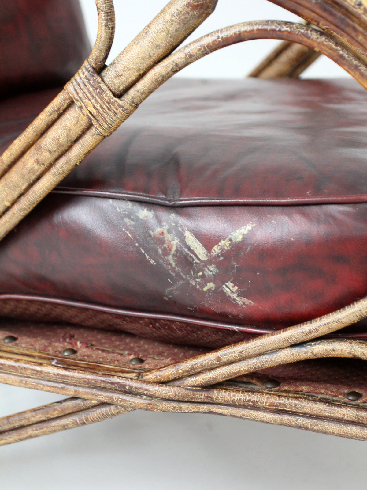 antique rattan lounge chair with oxblood cushions