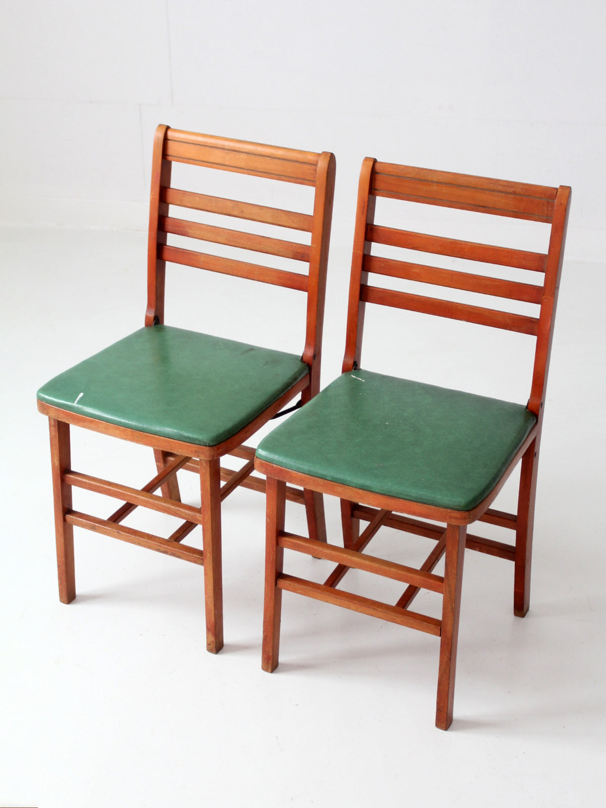 pair of 1950s wooden folding chairs with green seats