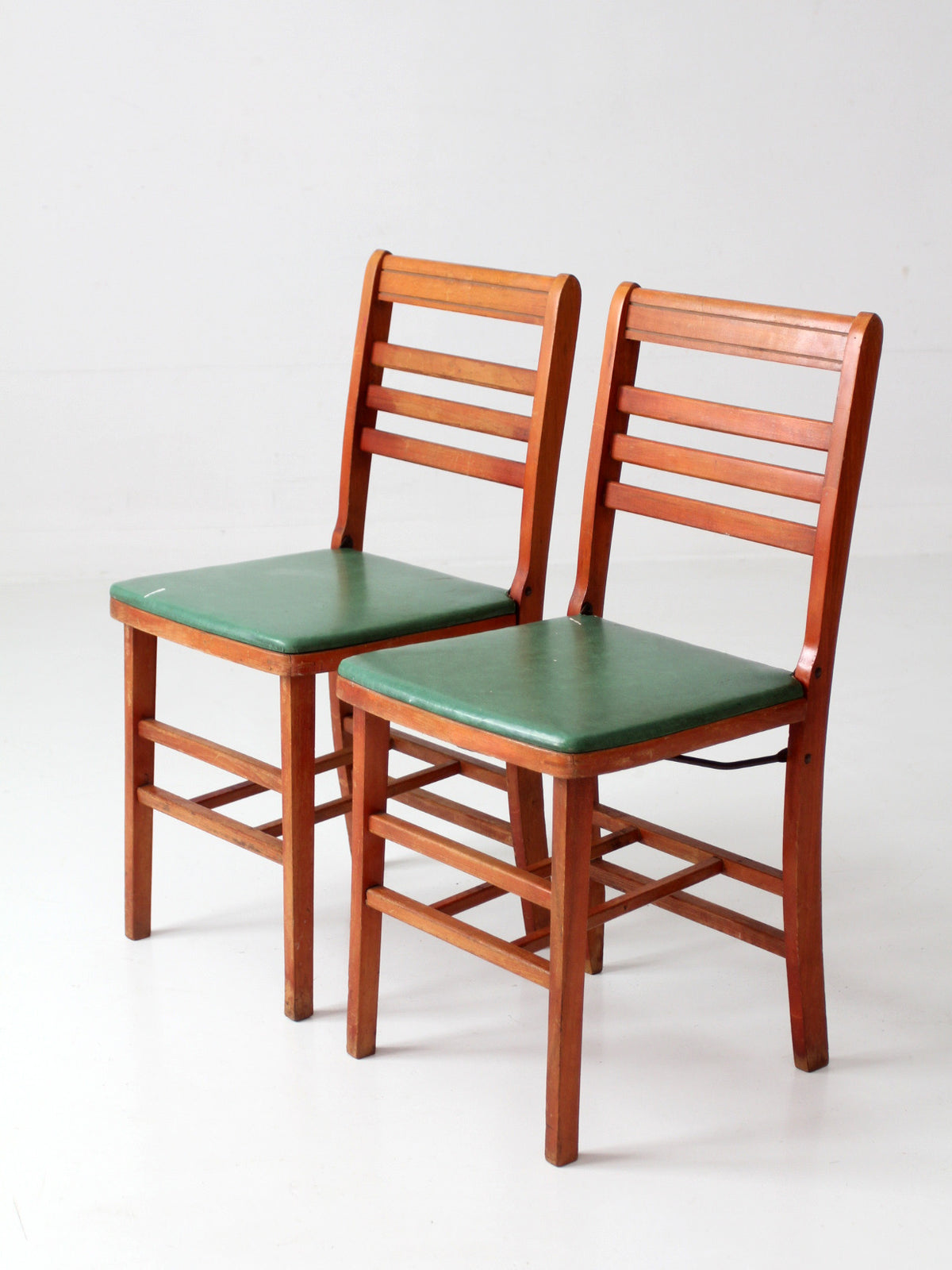 pair of 1950s wooden folding chairs with green seats