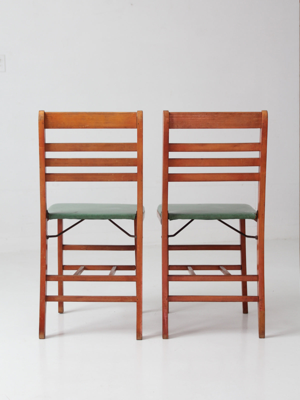 pair of 1950s wooden folding chairs with green seats