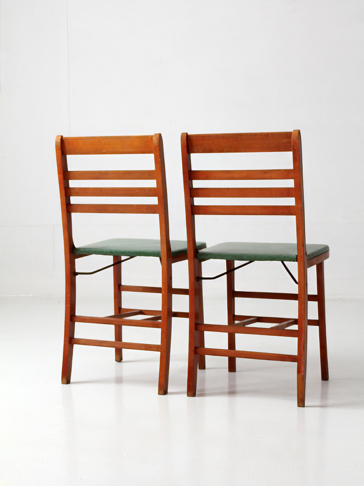 pair of 1950s wooden folding chairs with green seats