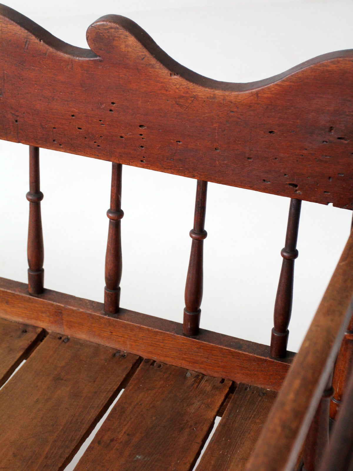antique 19th century wooden spindle back bench with scalloped crest rail